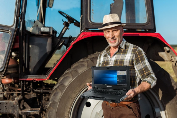 Landwirt mit robustem Laptop im Außeneinsatz